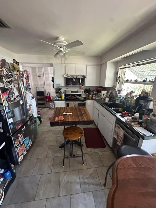 1559 San Roy Dr, Dunedin, FL 34698 - kitchen with stainless steel appliances, a sink, white cabinetry, dark countertops, and a ceiling fan