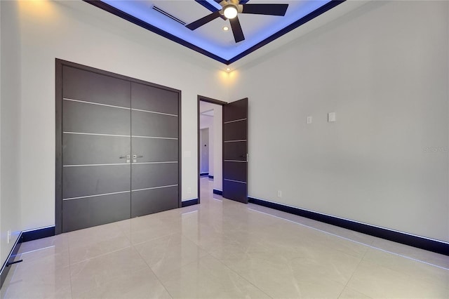 6534 Simone Shores Cir, Apollo Beach, FL 33572 - unfurnished bedroom featuring light tile patterned floors, a tray ceiling, ceiling fan, and baseboards
