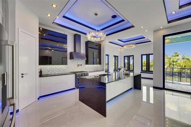6534 Simone Shores Cir, Apollo Beach, FL 33572 - kitchen with modern cabinets, wall chimney range hood, a chandelier, appliances with stainless steel finishes, and a raised ceiling