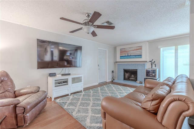 3968 Orchard Hill Cir, Palm Harbor, FL 34684 - living room featuring a ceiling fan, wood finished floors, a textured ceiling, a fireplace, and ornamental molding