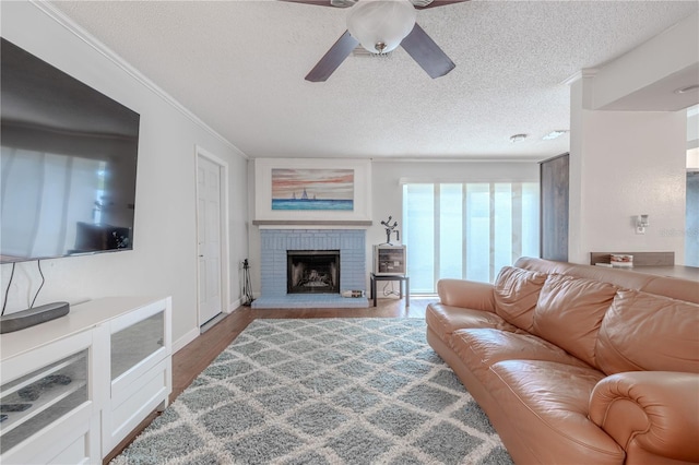 3968 Orchard Hill Cir, Palm Harbor, FL 34684 - living area with a textured ceiling, a ceiling fan, a brick fireplace, wood finished floors, and baseboards