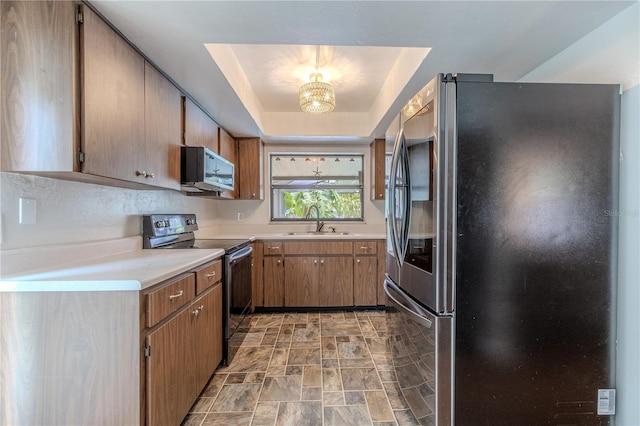 3968 Orchard Hill Cir, Palm Harbor, FL 34684 - kitchen featuring stainless steel appliances, a sink, stone finish floors, light countertops, and a tray ceiling