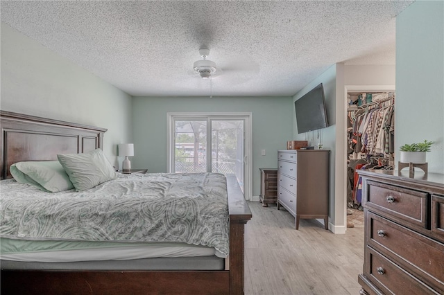 3968 Orchard Hill Cir, Palm Harbor, FL 34684 - bedroom with a spacious closet, light wood-style floors, a closet, a textured ceiling, and access to exterior