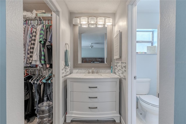 3968 Orchard Hill Cir, Palm Harbor, FL 34684 - bathroom featuring vanity, a walk in closet, toilet, and a textured ceiling