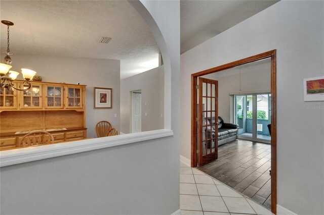 905 Balsamina Dr, Brandon, FL 33510 - hall with a chandelier, arched walkways, light tile patterned floors, baseboards, and a textured ceiling