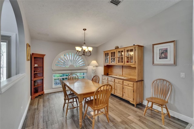 905 Balsamina Dr, Brandon, FL 33510 - dining room with light wood-type flooring, a textured ceiling, arched walkways, baseboards, and vaulted ceiling
