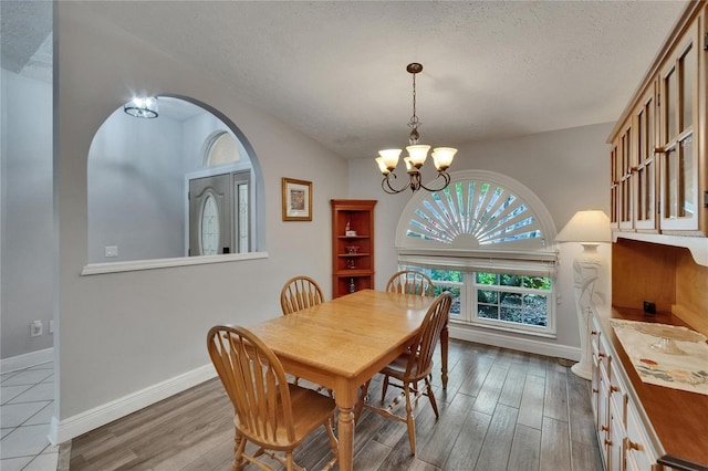 905 Balsamina Dr, Brandon, FL 33510 - dining space featuring a textured ceiling, arched walkways, a chandelier, wood finished floors, and baseboards