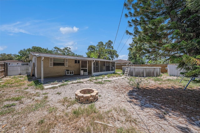 11486 92nd St N, Largo, FL 33773 - rear view of house with a fire pit, a sunroom, a fenced backyard, and a patio area
