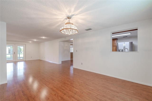 12220 Twin Branch Acres Rd, Tampa, FL 33626 - spare room featuring a chandelier, wood finished floors, baseboards, and a textured ceiling