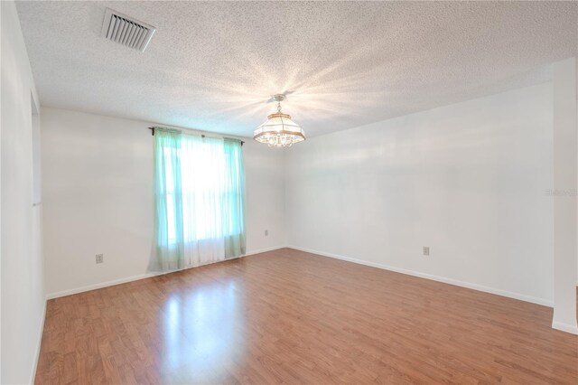 12220 Twin Branch Acres Rd, Tampa, FL 33626 - empty room featuring wood finished floors, a chandelier, a textured ceiling, and baseboards