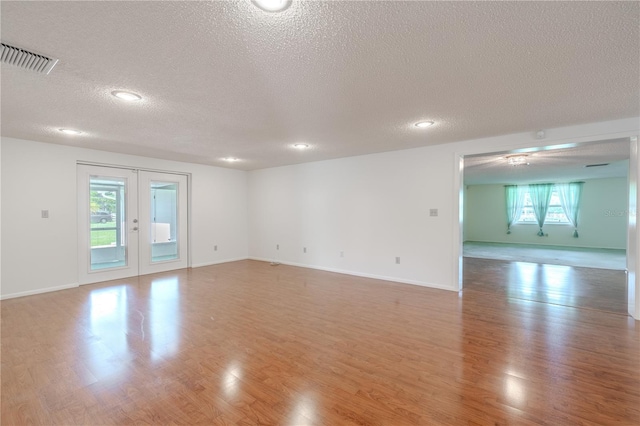 12220 Twin Branch Acres Rd, Tampa, FL 33626 - empty room featuring a textured ceiling, healthy amount of natural light, light wood finished floors, french doors, and recessed lighting