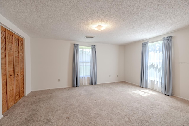 12220 Twin Branch Acres Rd, Tampa, FL 33626 - unfurnished bedroom with multiple windows, light colored carpet, a textured ceiling, a closet, and baseboards