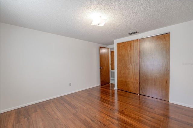 12220 Twin Branch Acres Rd, Tampa, FL 33626 - unfurnished bedroom featuring wood finished floors, a closet, a textured ceiling, and baseboards