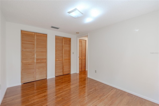 12220 Twin Branch Acres Rd, Tampa, FL 33626 - unfurnished bedroom featuring two closets, light wood-style flooring, and baseboards