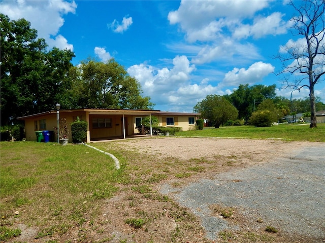 10308 Fore Dr, Tampa, FL 33612 - back of house featuring driveway, an attached carport, and a lawn