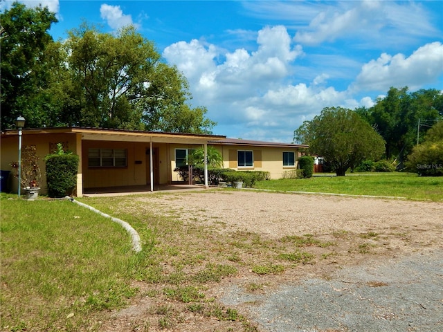 10308 Fore Dr, Tampa, FL 33612 - ranch-style home with dirt driveway, an attached carport, and a front lawn