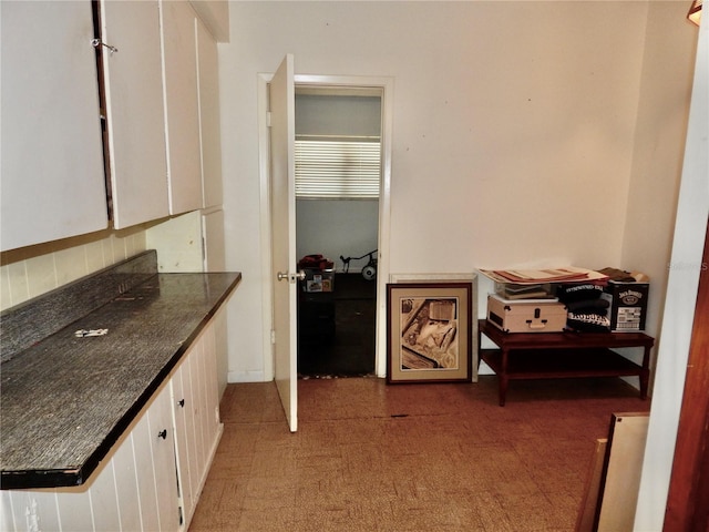 10308 Fore Dr, Tampa, FL 33612 - kitchen with white cabinetry, dark countertops, light carpet, and decorative backsplash
