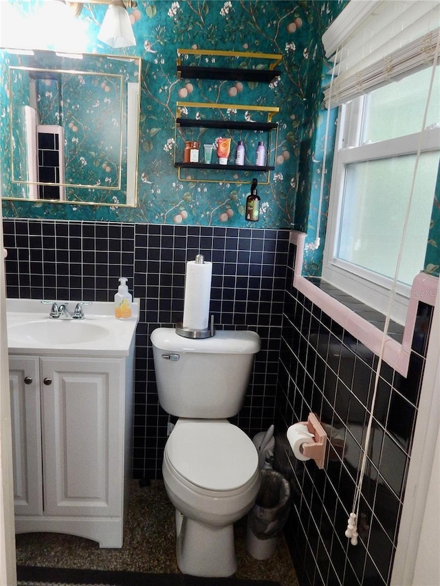 10308 Fore Dr, Tampa, FL 33612 - bathroom featuring wallpapered walls, tile walls, toilet, a wainscoted wall, and vanity