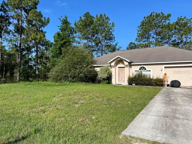 18063 Parrot Rd, Weeki Wachee, FL 34614 - view of front of property with driveway, a garage, a front yard, and stucco siding