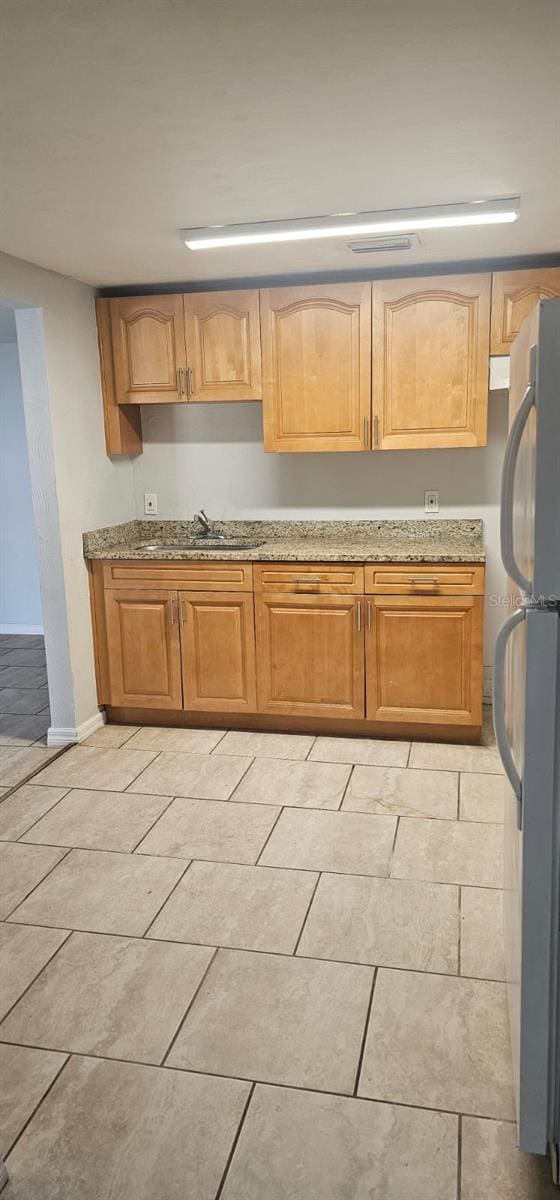9307 N 16th St, Tampa, FL 33612 - kitchen with freestanding refrigerator, light stone countertops, a sink, and baseboards