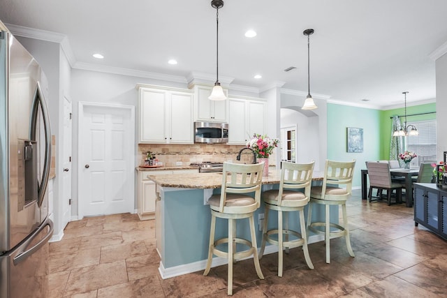 5401 Match Point Pl, Lithia, FL 33547 - kitchen featuring appliances with stainless steel finishes, decorative backsplash, white cabinets, a kitchen bar, and ornamental molding