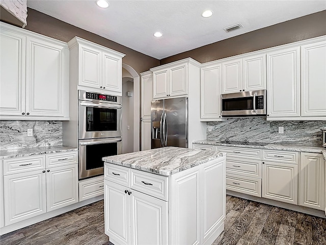 1443 Obear Ct, Wesley Chapel, FL 33543 - kitchen with stainless steel appliances, arched walkways, recessed lighting, dark wood-style flooring, and backsplash