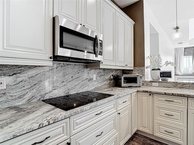1443 Obear Ct, Wesley Chapel, FL 33543 - kitchen featuring stainless steel microwave, black electric stovetop, light stone counters, and white cabinets