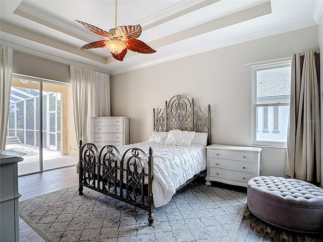 1443 Obear Ct, Wesley Chapel, FL 33543 - bedroom with access to exterior, multiple windows, a tray ceiling, wood finished floors, and ornamental molding