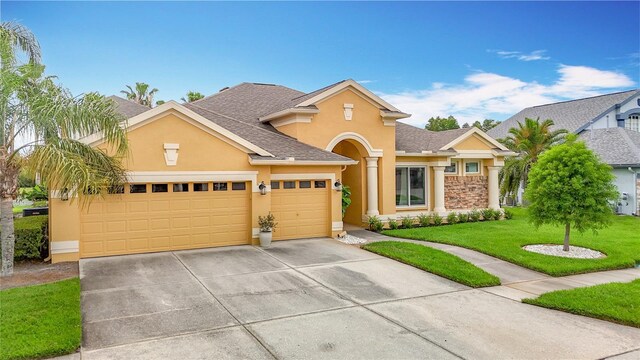 1443 Obear Ct, Wesley Chapel, FL 33543 - traditional-style home with stucco siding, concrete driveway, an attached garage, a front yard, and roof with shingles
