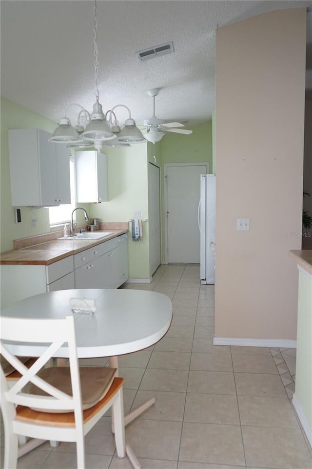 2325 Brookfield Greens Cir Unit 41, Sun City Center, FL 33573 - kitchen with a sink, freestanding refrigerator, white cabinets, light tile patterned floors, and baseboards