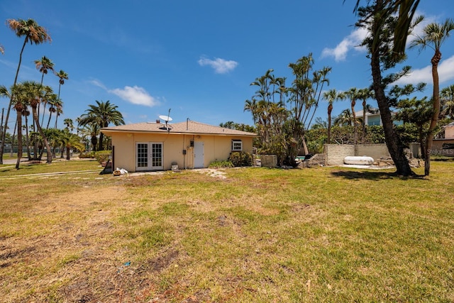 3111 S De Bazan Ave, St Pete Beach, FL 33706 - back of property with french doors, a yard, and stucco siding