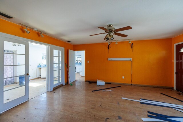 3111 S De Bazan Ave, St Pete Beach, FL 33706 - unfurnished living room featuring ceiling fan, french doors, wood finished floors, and rail lighting