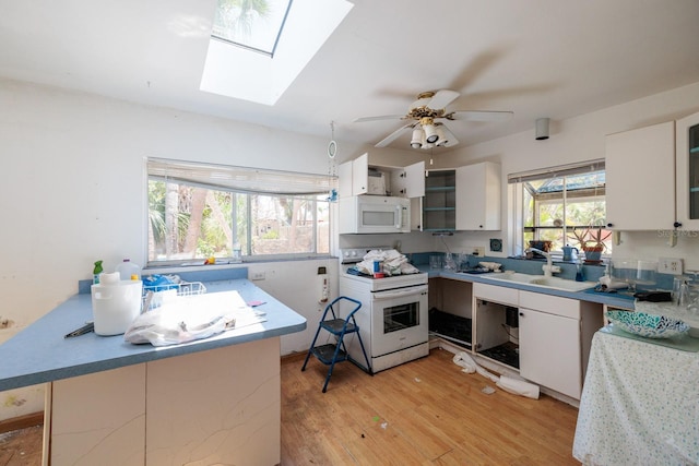 3111 S De Bazan Ave, St Pete Beach, FL 33706 - kitchen featuring white appliances, a sink, a skylight, and light wood-style floors