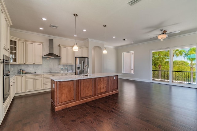 4353 Dewey Dr, New Port Richey, FL 34652 - kitchen featuring cream cabinets, wall chimney range hood, stainless steel fridge, arched walkways, and recessed lighting
