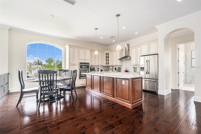 4353 Dewey Dr, New Port Richey, FL 34652 - kitchen with stainless steel appliances, wall chimney range hood, arched walkways, light countertops, and dark wood finished floors