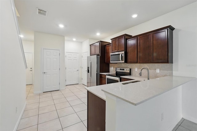 5024 Sylvester Loop, Tampa, FL 33610 - kitchen with stainless steel appliances, a sink, light tile patterned floors, backsplash, and dark brown cabinetry