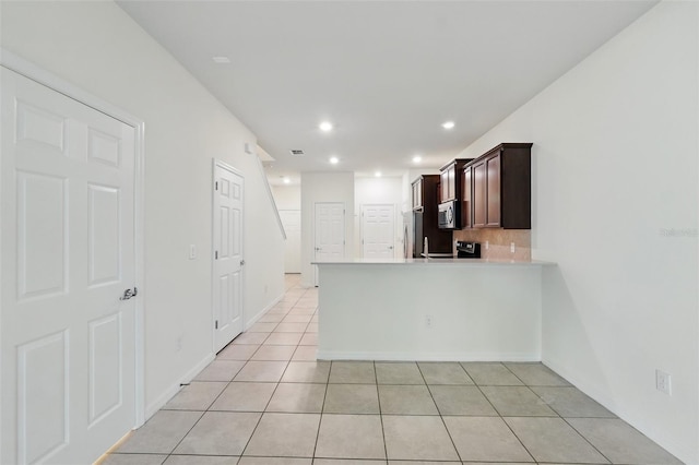 5024 Sylvester Loop, Tampa, FL 33610 - kitchen with appliances with stainless steel finishes, light tile patterned floors, light countertops, a peninsula, and dark brown cabinetry