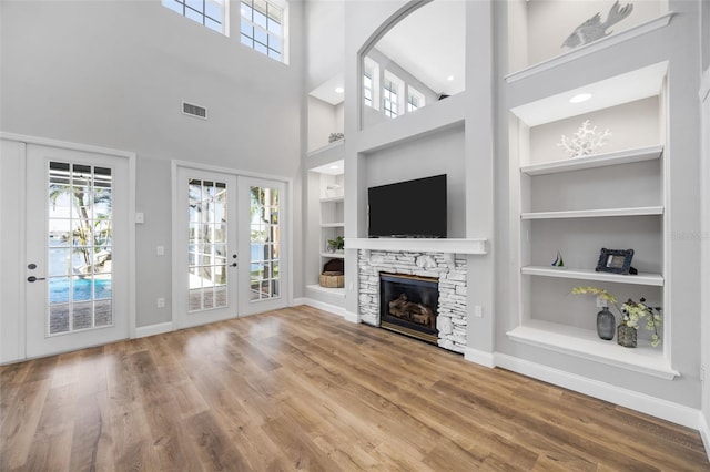 5225 Brighton Shore Dr, Apollo Beach, FL 33572 - unfurnished living room featuring built in features, french doors, baseboards, wood finished floors, and a towering ceiling