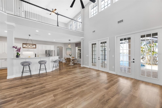 5225 Brighton Shore Dr, Apollo Beach, FL 33572 - living room featuring french doors, light wood-type flooring, a towering ceiling, ceiling fan, and arched walkways