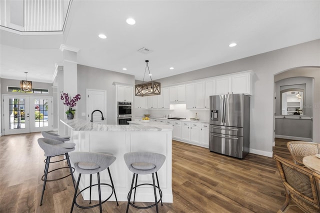 5225 Brighton Shore Dr, Apollo Beach, FL 33572 - kitchen featuring stainless steel appliances, dark wood-style floors, arched walkways, white cabinetry, and recessed lighting