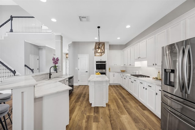 5225 Brighton Shore Dr, Apollo Beach, FL 33572 - kitchen with appliances with stainless steel finishes, a sink, a kitchen island, white cabinets, and recessed lighting