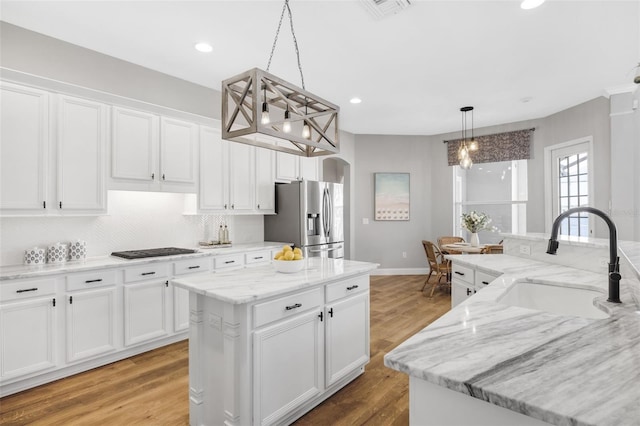 5225 Brighton Shore Dr, Apollo Beach, FL 33572 - kitchen featuring stainless steel fridge, a sink, a kitchen island, arched walkways, and white cabinetry
