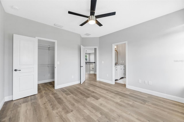 5225 Brighton Shore Dr, Apollo Beach, FL 33572 - unfurnished bedroom with light wood finished floors, a walk in closet, baseboards, a closet, and connected bathroom