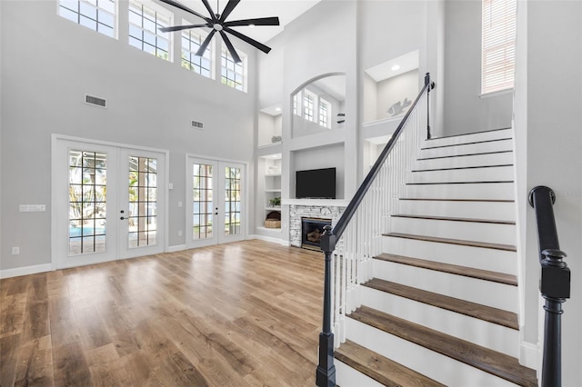 5225 Brighton Shore Dr, Apollo Beach, FL 33572 - staircase featuring french doors, built in features, a fireplace, wood finished floors, and high vaulted ceiling