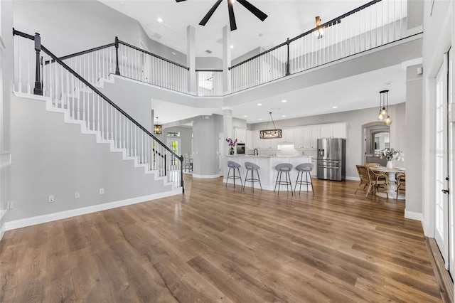 5225 Brighton Shore Dr, Apollo Beach, FL 33572 - unfurnished living room with ceiling fan, a high ceiling, dark wood-style floors, stairs, and baseboards