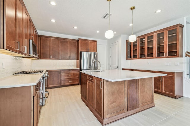 511 Roanoke St, Dunedin, FL 34698 - kitchen with stainless steel appliances, tasteful backsplash, glass insert cabinets, a kitchen island with sink, and light countertops