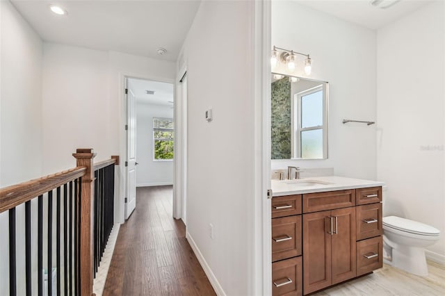 511 Roanoke St, Dunedin, FL 34698 - bathroom featuring vanity, wood finished floors, toilet, baseboards, and recessed lighting