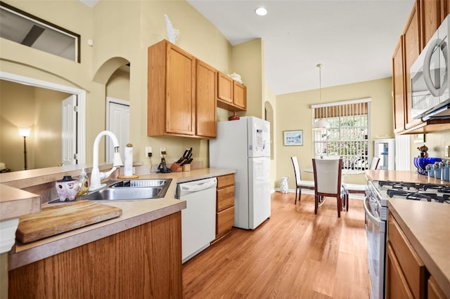 31108 Whitlock Dr, Wesley Chapel, FL 33543 - kitchen with white appliances, a sink, light wood-style flooring, high vaulted ceiling, and light countertops