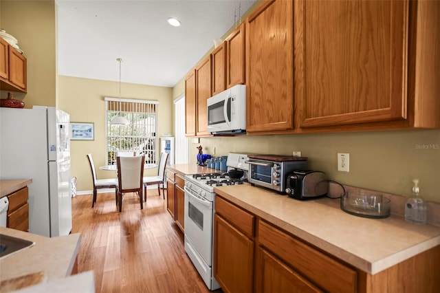 31108 Whitlock Dr, Wesley Chapel, FL 33543 - kitchen featuring white appliances, light wood-type flooring, light countertops, brown cabinetry, and recessed lighting