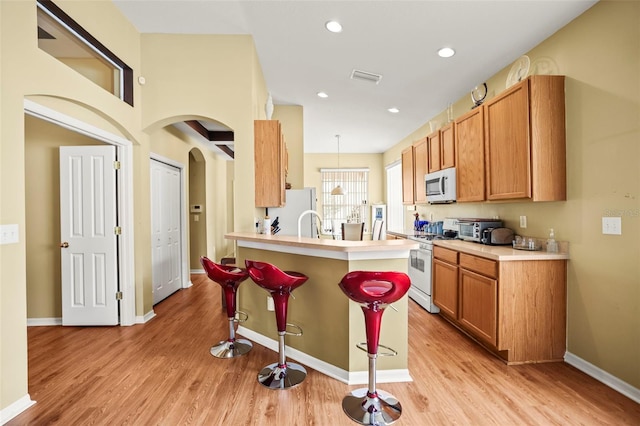 31108 Whitlock Dr, Wesley Chapel, FL 33543 - kitchen featuring white appliances, a breakfast bar, light wood-style flooring, light countertops, and recessed lighting